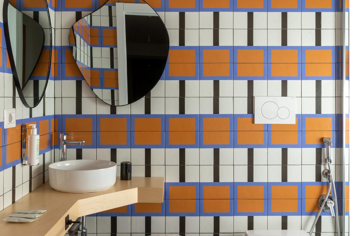 Apartment bathroom in Rome Monti district with modern sink, shower and geometric orange and blue tiles - Salotto Monti, BZAR hotels in Rome