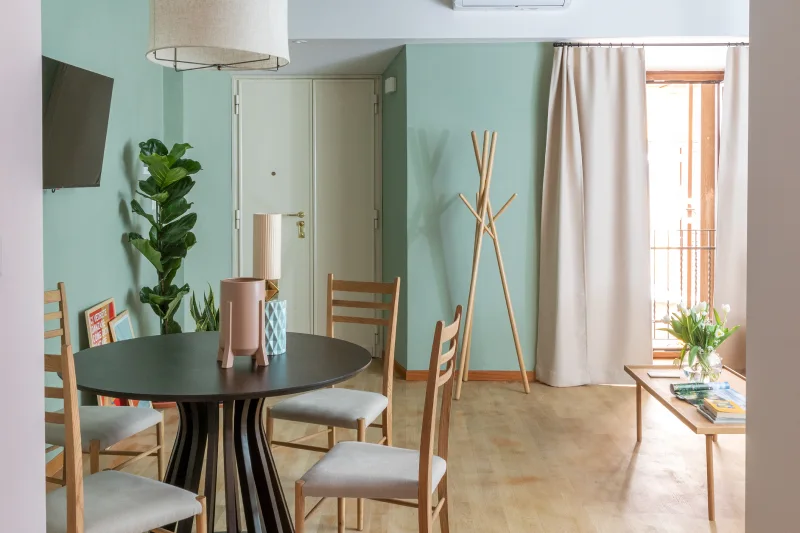 Zona pranzo appartamento nel rione Monti Roma con tavolo, sedie in legno e balcone con luce naturale - Salotto Monti, BZAR hotels a Roma