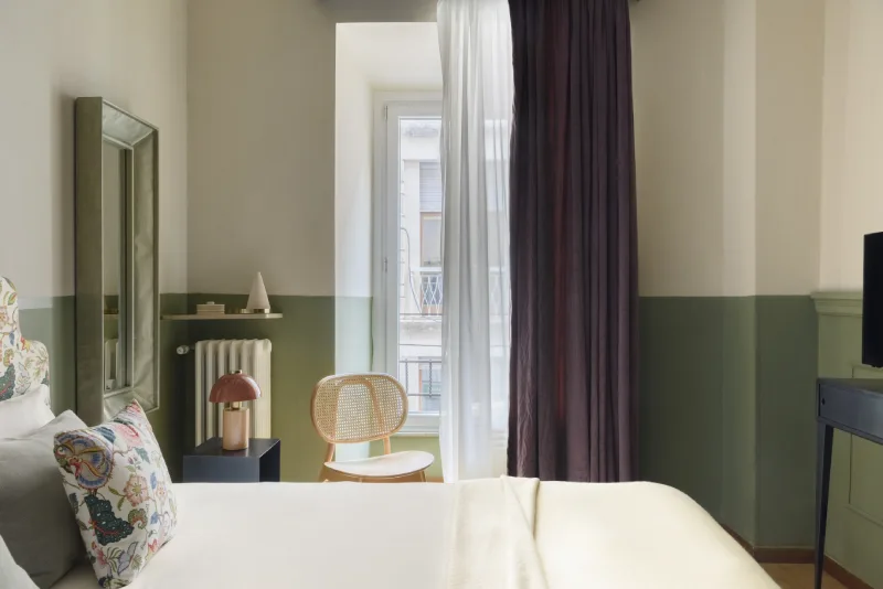 Camera matrimoniale appartamento nel quartiere Monti Roma con letto elegante, tende scure e vista su edifici storici - Salotto Monti, BZAR hotels a Roma