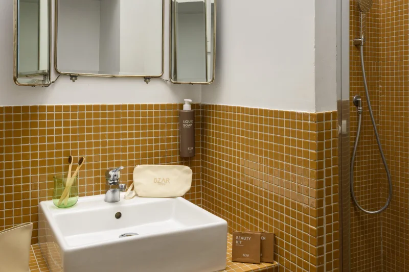 Bagno appartamento nel rione Monti Roma con doccia, piastrelle color ocra, lavabo moderno e accessori curati - Salotto Monti, BZAR hotels a Roma