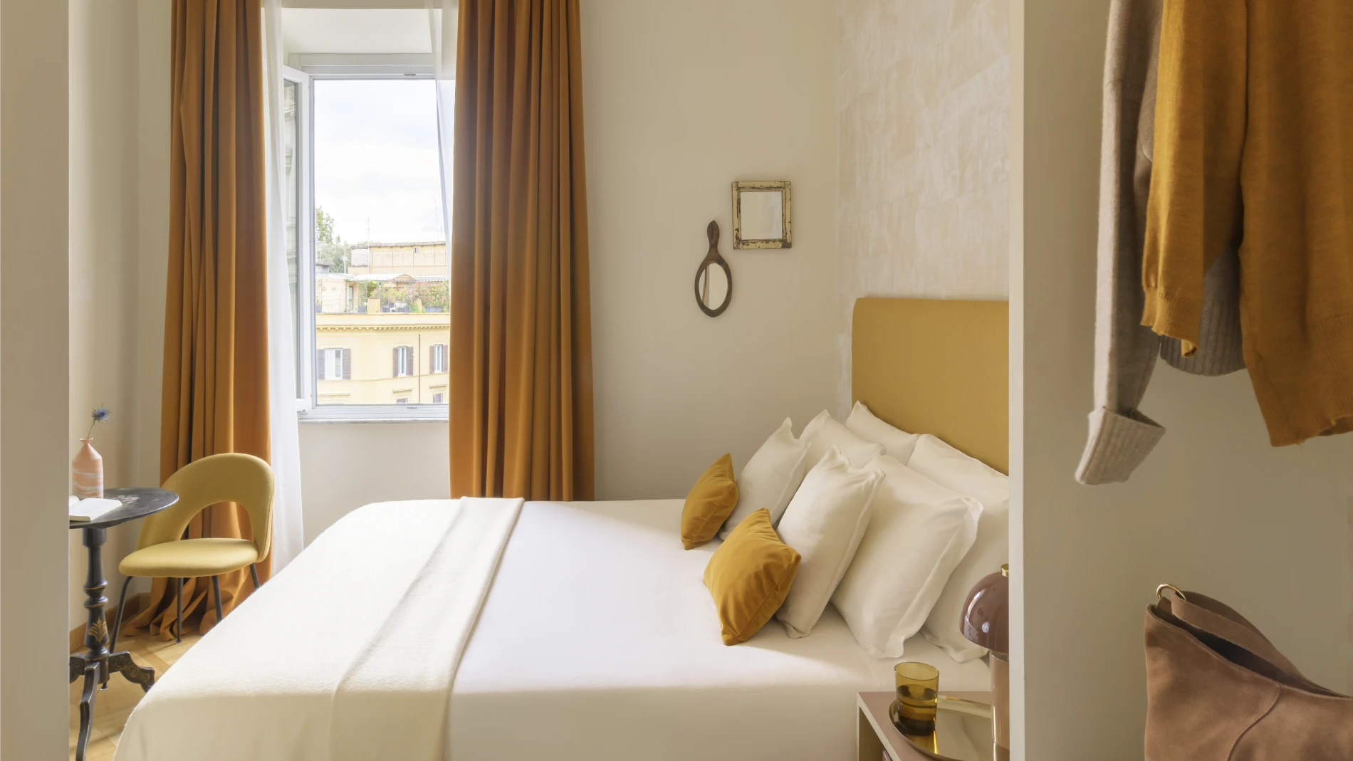 Double room in Rome Monti district with white bed, ochre cushions, elegant curtains and view of historic buildings - Salotto Monti, BZAR hotels in Rome