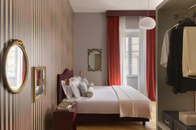 Junior Suite in Rome Monti district with double bed, striped wall, gilded mirrors, red curtains and open wardrobe - Salotto Monti, BZAR hotels in Rome