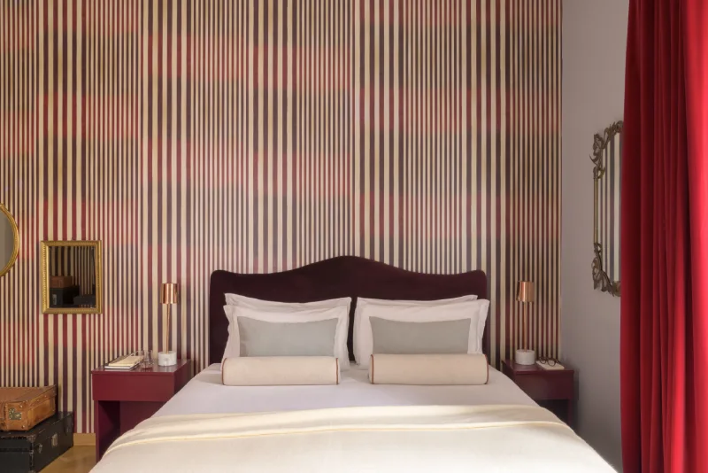 Double bed in Junior Suite in Rome Monti district with burgundy headboard, striped wallpaper and design bedside tables - Salotto Monti, BZAR hotels in Rome