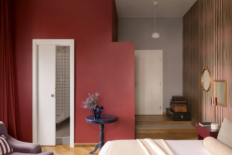 Junior Suite in Rome Monti district with red feature wall, small table corner, raised entry area, bathroom door and retro details - Salotto Monti, BZAR hotels in Rome