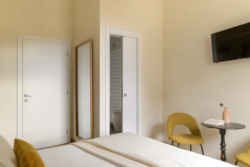 Room interior in Rome Monti with bed, full-length mirror, bathroom access and essential modern furnishings - Salotto Monti, BZAR hotels in Rome