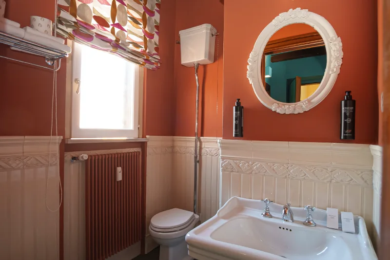 Elegant bathroom in Rome Monti district with classic sink, oval mirror, decorative tiles and natural light - Salotto Monti, BZAR hotels in Rome