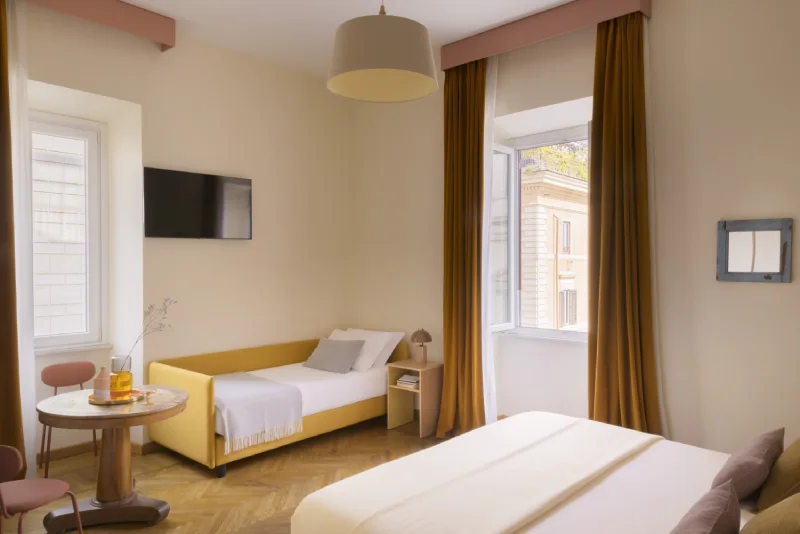 Triple room in Rome Monti district with double bed and yellow sofa bed, round table, wall TV and bright double windows - Salotto Monti, BZAR hotels in Rome