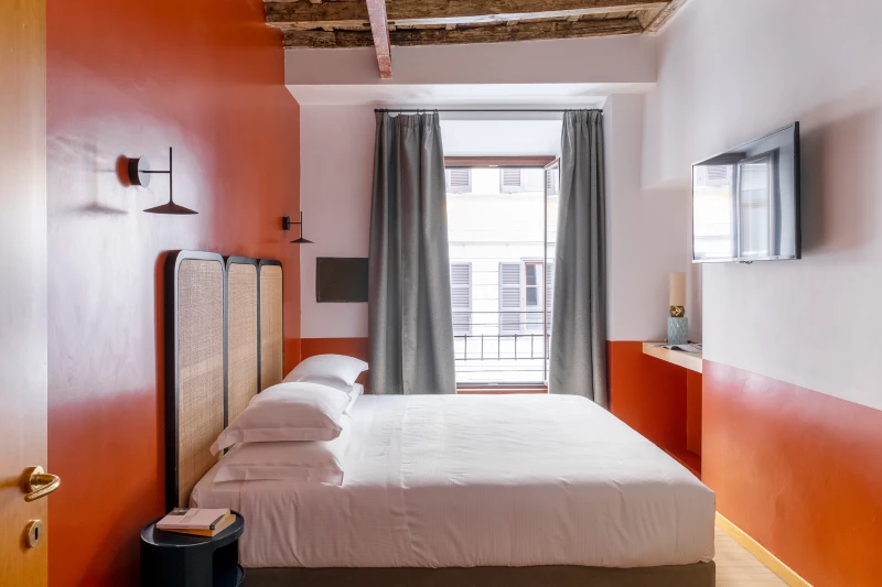 Seconda camera matrimoniale nel rione Monti Roma con pareti rosse, travi a vista, letto design e illuminazione sospesa - Salotto Monti, BZAR hotels a Roma